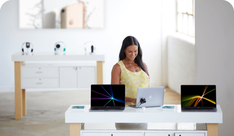 Mulher olhando para laptops em uma mesa em uma loja de operadoras de celular