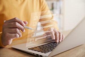 Gerente de loja preenchendo uma lista de verificação de auditoria de prevenção de perdas em um laptop.