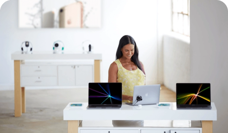Mulher olhando para laptops em uma mesa em uma loja de operadoras de celular