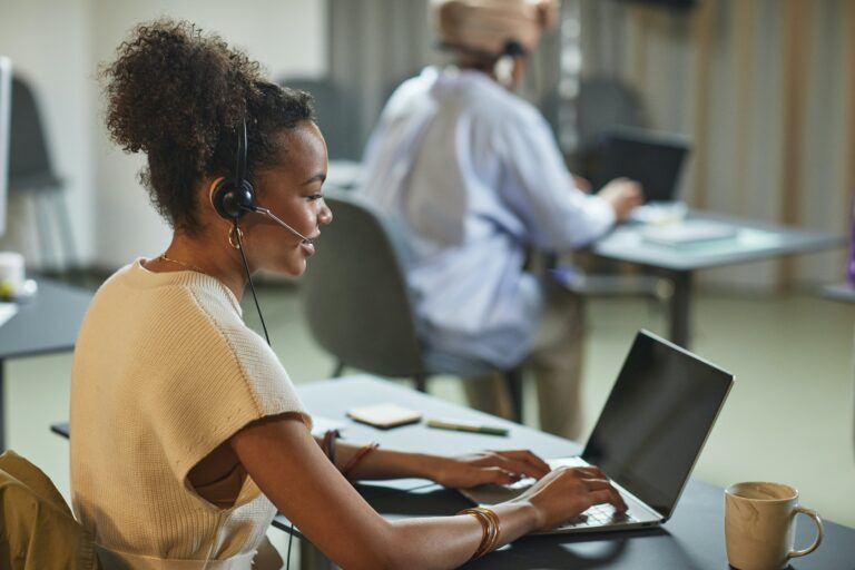 Mulher sentada em um laptop com um fone de ouvido de atendimento ao cliente