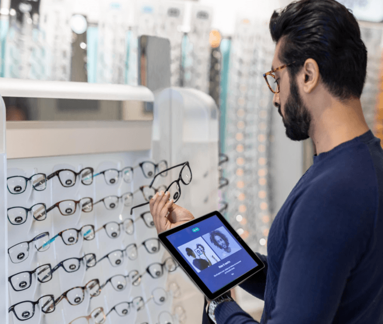 Homem segurando óculos enquanto segura um tablet portátil