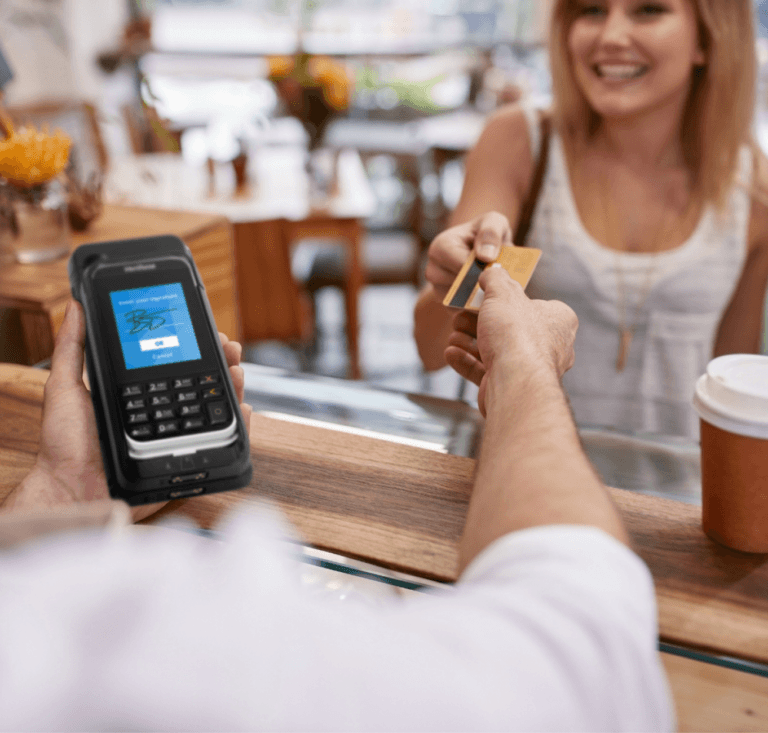 Mulher entregando um cartão de crédito a um trabalhador segurando um mPOS