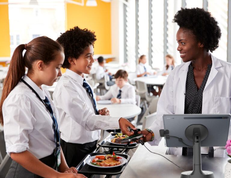 Funcionário da escola em frente ao suporte de tablet NE150 com dois alunos de uniforme